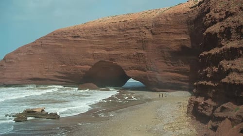 Dramatic Red Rock Archway on a Sandy Beach