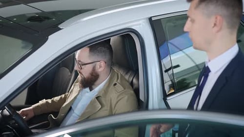 an Adult Man Sits in the Salon of a New Car in a Dealership
