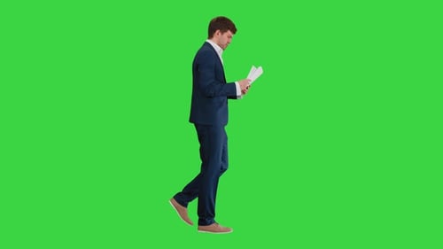 Concentrated Businessman Reading Documents or Report While Walking on a Green Screen, Chroma Key.