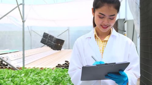 Young Scientist Inspecting Plants in Greenhouse