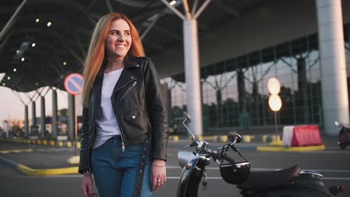 Woman Smiles Near Motorcycle in Urban Setting
