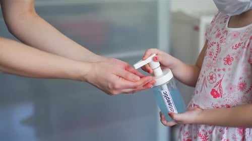 Petite fille appliquant un antiseptique sur les mains de maman