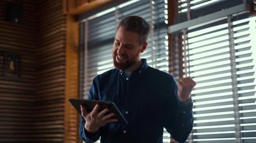Man Smiles, Celebrates Success While Using Tablet
