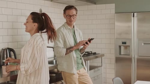 Young Couple Use Phone Together in Kitchen