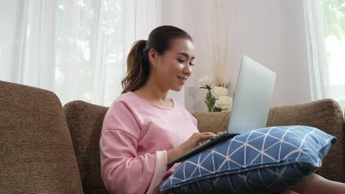 Woman Using Laptop on Couch at Home