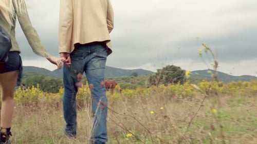 Back View of Beautiful Blond Young Girl and Man Couple in Love Walks Outdoor in Nature Keeping Hands