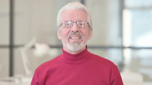 Senior Man Waving and Talking Directly To Camera