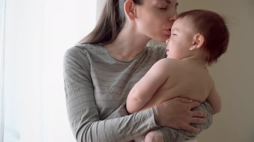 Loving Mother Holds Young Child by Window