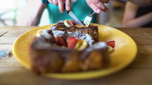 Slowmotion shot of a guy cutting some frenchtoast.