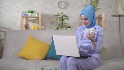 Woman with Hijab Using Laptop with Pills