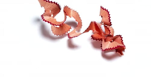 Red Pencil Shavings Falling Against White Background