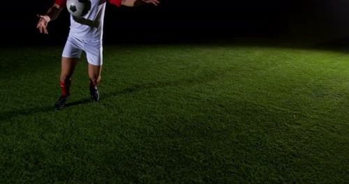 Soccer Player Skillfully Kicking Ball on Field at Night