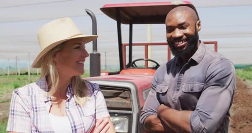 Smiling Farmers Standing Near Tractor on Farmland