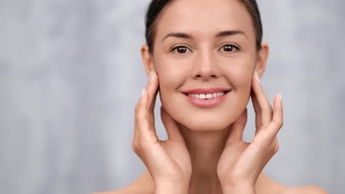 Smiling Young Adult Woman Touches Her Face