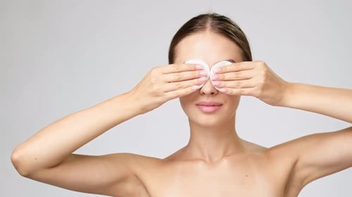 Woman Puts Cotton Pad on Eyes, Smiles