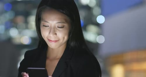 Femme d'affaires travaillant sur un téléphone portable en ville la nuit