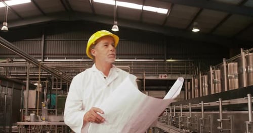 Worker looking at blue print while examining