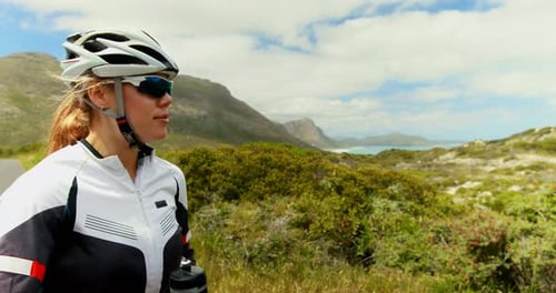 Female cyclist drinking water at countryside road 4k