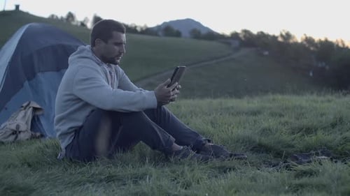 Young Man Using Tablet in Nature Mountain Outdoor at Sunrise or Sunset Slow Motion