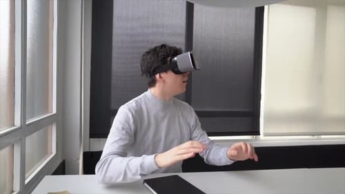 Youn businessman sitting in office using virtual reality simulator