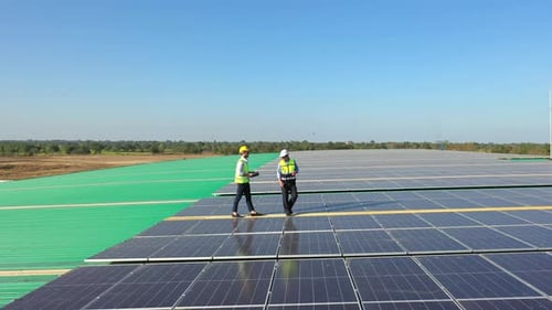 4K Professional engineer using tablet maintaining solar cell panels together on building rooftop.