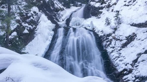Icy Waterfall Flows Through Snowy Winter Landscape