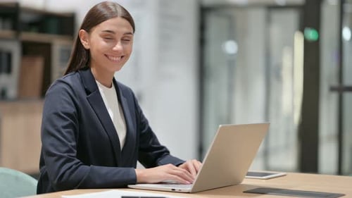 Woman Typing on Laptop in Bright Office, Smiling