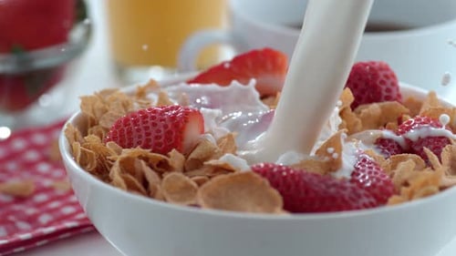 Milk Being Poured onto Cereal and Strawberries