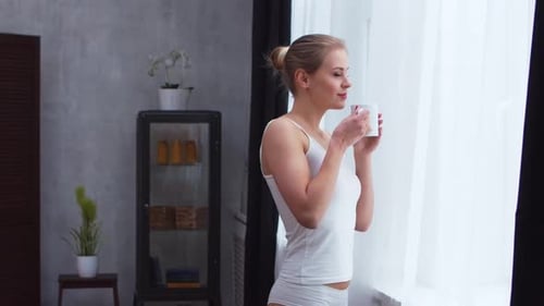 Jeune fille se tient devant la fenêtre
