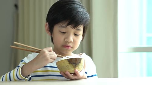 Child Eats Rice with Chopsticks in Home