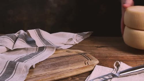 Women hands put wheels of fresh homemade cheese on a wooden board close up