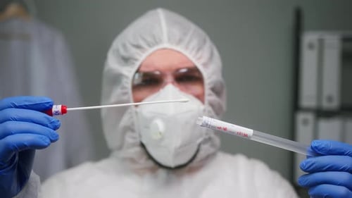 Closeup of PCR Test in Laboratory Doctor Holding COVID19 Coronavirus Swab Collection Kit Wearing PPE