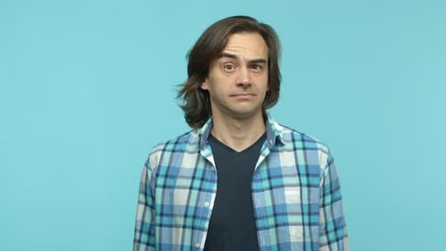 Man Looks Confused, Winking on Blue Background