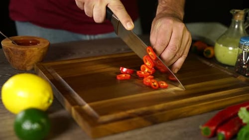 Man slicing hot red chili pepper on cutting board