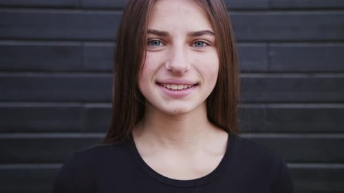 An Attractive Young Lady Straightens Her Hair and Smiles Outdoors. Close-up Shot