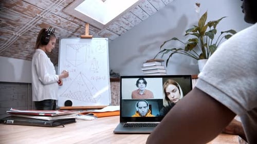 Eine Online-Mathematikstunde - Frau steht am Vorstand und ihre Schüler auf dem Bildschirm hören ihr zu