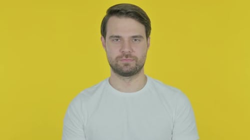 Glücklicher junger Mann mit zwinkerndem Auge auf gelbem Hintergrund