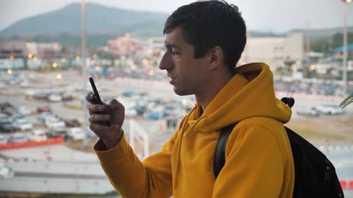 Man Using Smartphone Near City Parking Lot