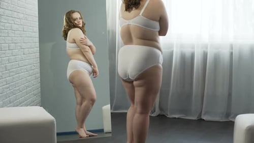 Woman Looks in Mirror in Underwear