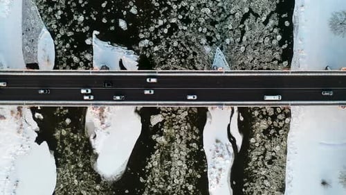 Stadtverkehr auf der Brücke über den gefrorenen Fluss im Winter