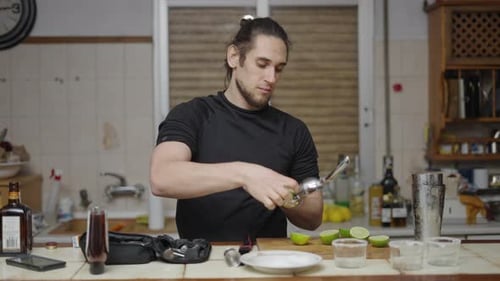 Young Adult Man Squeezing Limes Into Cocktail Shaker