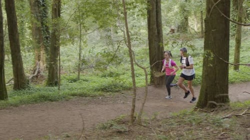 Man and Woman in Sportswear Running on Trail in Forest