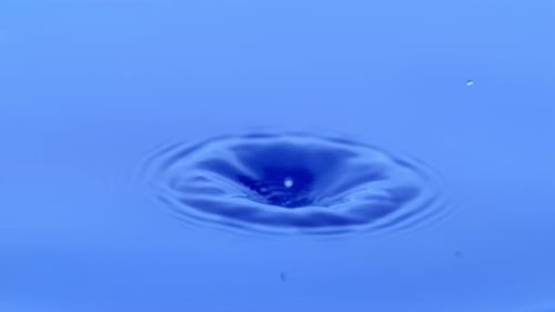 Water Drop Impacting Blue Liquid Surface