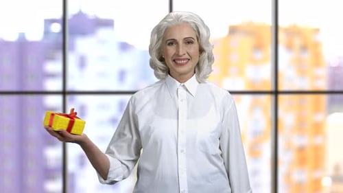 Smiling Senior Woman Holds Out Birthday Gift
