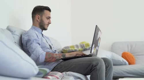Young Adult Man Working on Laptop at Home
