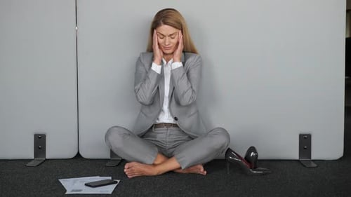 Stressed Woman in Suit Sitting Barefoot on Floor