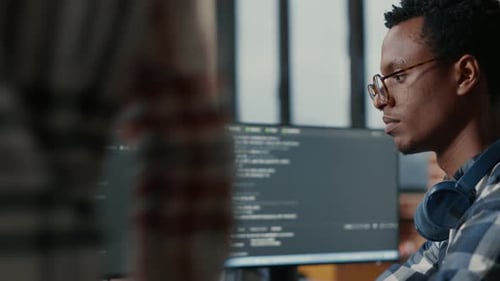 Retrato de desarrollador de software enfocado escribiendo código arreglando gafas sentado en el escritorio