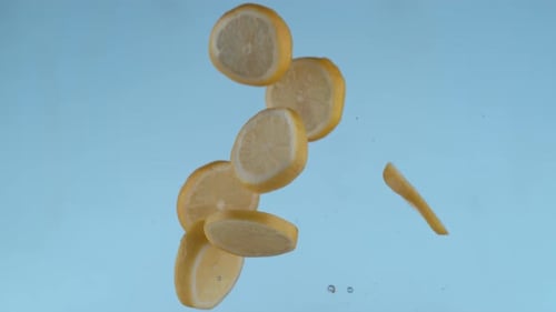 Lemon Slices Falling Against a Blue Background