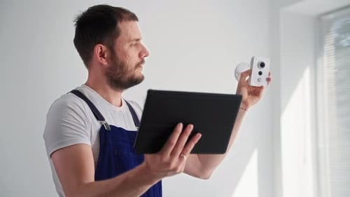 Worker configuring security camera with tablet technology