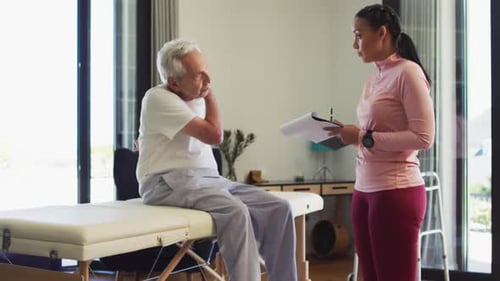 Video of biracial female physiotherapist examining caucasian senior man